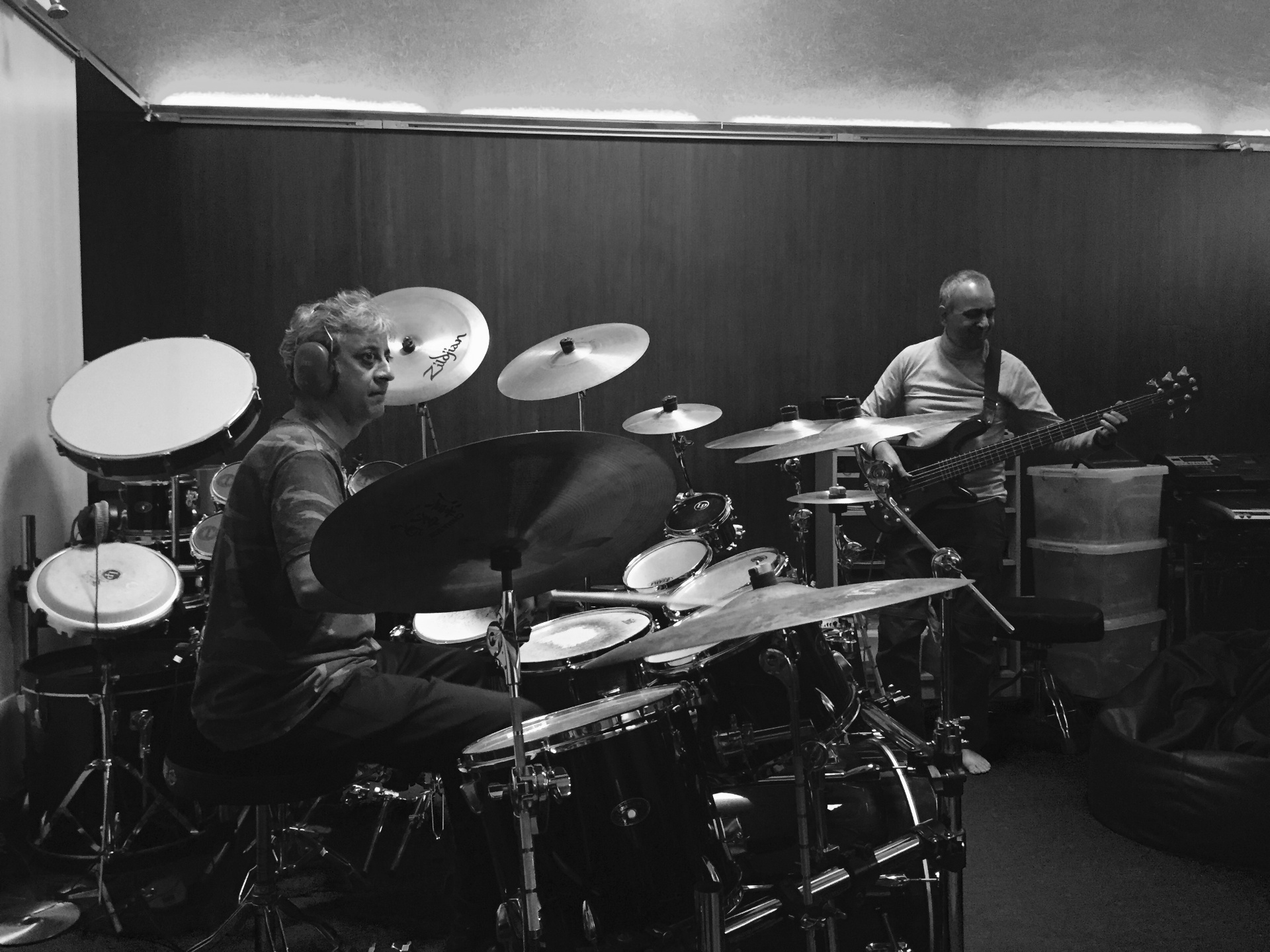 Black-and-white rehearsal moment of Roberto at the drum kit alongside the bassist.